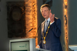 Ein Mann in Anzug und goldener Kette spricht an einem Rednerpult der Max-Planck-Gesellschaft.
